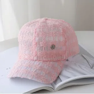 Detail of pink lace baseball cap with intricate mesh patterns and vintage metal button