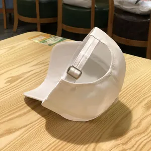 Close-up of adjustable strap and silver metal buckle on a white cotton baseball cap