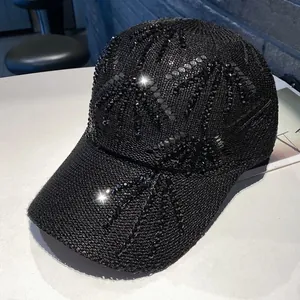 Dettaglio cappellino nero in maglia con strass scintillanti a motivo di palma
