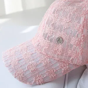 Close-up of pink lace and tweed sun cap with silver metal M logo and shiny silk details