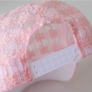 Detail of pink lace baseball cap featuring intricate hollow patterns and plastic snapback closure