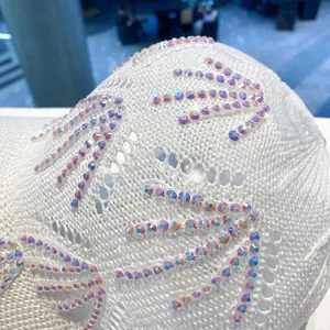 Dettaglio macro di un cappellino in maglia bianca con strass iridescenti a motivo floreale