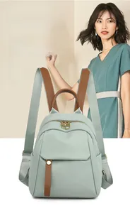 Close-up of light green oxford fabric backpack with brown lychee leather details and gold hardware