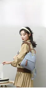 Side view of a light blue Oxford fabric backpack with brown leather accents on a model
