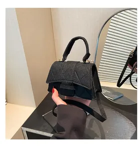 Detail of black quilted crossbody bag with textured fabric and metallic buckle clasp