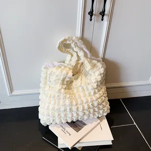 Cloud pleat tote bag in creamy white with lace bow detail on minimalist book display