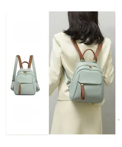 Close-up of mint green Oxford cloth backpack with brown leather accents and flap pocket