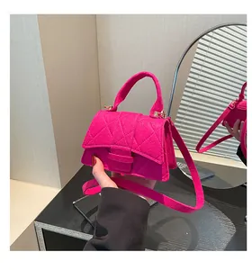 Detail of rose red mini handbag with textured quilting and gold metal hardware link