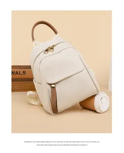Close-up of beige Oxford cloth backpack with brown contrast handle and metal zipper