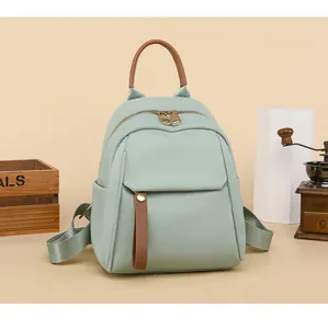 Detail of mint green waterproof nylon mini backpack with brown leather trim and side pocket