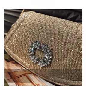 Gros plan du sac de soirée doré pailleté avec une boucle en matériel ornée de cristaux