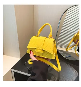 Detail of a bright yellow quilted crossbody bag with top handle and matching shoulder strap