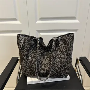 Gray leopard print tote bag placed on a book over a chair in a minimalist office setting