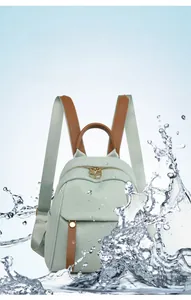Waterproof mini green backpack with leather straps shown with dynamic water splashes