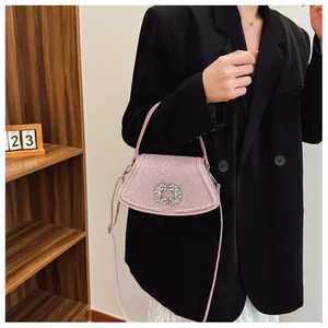 Détail du sac à bandoulière rose scintillant avec boucle en strass sur un blazer noir