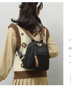 Side view of small black oxford fabric backpack with brown leather accents on female model