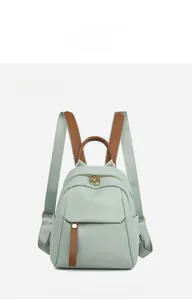 Detail of mint green oxford fabric backpack with brown leather accents and gold hardware