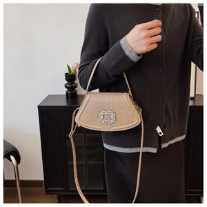Sac à main chic pailleté champagne avec boucle en cristal porté sur l'épaule par un mannequin