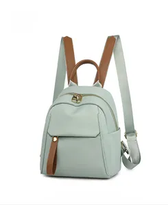 Detail view of mint green oxford fabric mini backpack with brown faux leather handles
