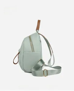 Side view of mint green Oxford cloth backpack with leather handle and golden hardware