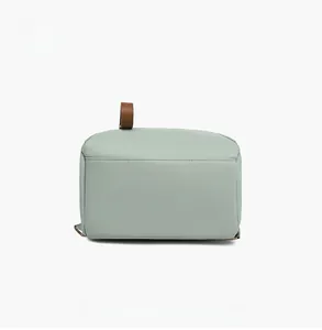 Detail view of the flat stitched bottom and brown leather handle on a light green oxford bag