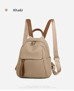 Front view of khaki oxford fabric backpack showing leather details and functional pockets