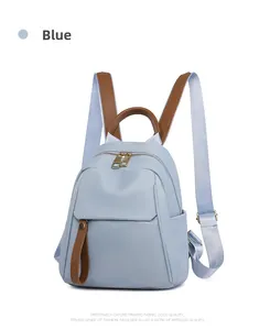 Close-up of blue Oxford cloth backpack featuring brown leather handles and gold hardware