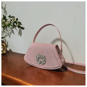 Gros plan sur un sac rose pailleté avec boucle en strass et fine bandoulière élégante
