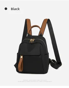 Detail view of black oxford fabric backpack with brown leather trim and golden zippers