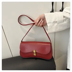 Detail of dark red matte leather underarm bag featuring a vintage golden metal clasp