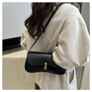 Detail of minimalist black underarm bag featuring a metallic gold oval twist lock closure