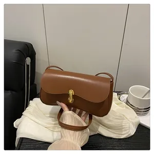 Detail of a brown leather shoulder bag featuring a smooth matte texture and gold metal buckle