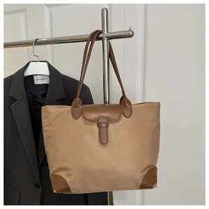 Close-up of khaki nylon tote bag with dark brown leather straps and metal buckle detail
