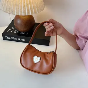 Brown retro PU leather crescent bag with heart bow detail, shown in a cozy setting