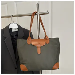 Detail of green nylon tote bag with brown leather reinforcement and sturdy stitching