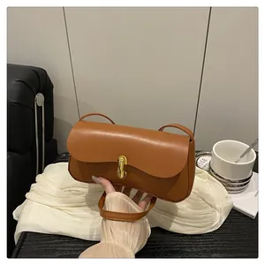 Detailed view of brown leather baguette bag with elegant gold metal twist lock buckle