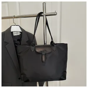 Detail of black nylon tote bag with faux leather reinforcement and stylish buckle flap