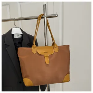 Detail view of brown Oxford tote bag with yellow leather trim and reinforced base corners