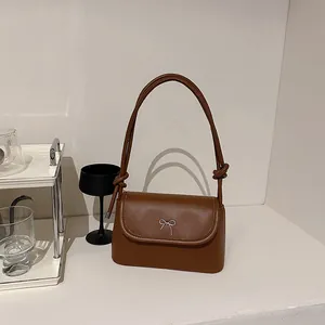 Brown faux leather crossbody bag with silver bow detail and knotted shoulder strap