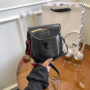 Glossy black mini saddle bag with strawberry charms and adjustable shoulder strap