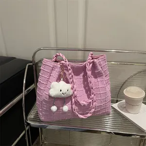 Pink textured tote bag with braided handles and cloud charm on a stylish glass shelf