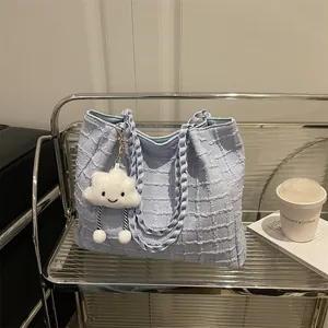 Light blue tweed tote bag with cloud charm on modern shelf, 2025 autumn fashion