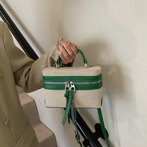 Fashionable box-shaped handbag in beige woven fabric with green leather trim accents