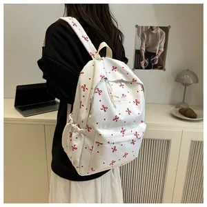 Détail d'un sac à dos blanc avec nœuds rouges et étiquette de mode sur le devant