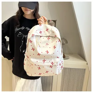 Détail du sac à dos blanc avec motif à nœuds rouges et étiquette de marque Fashion