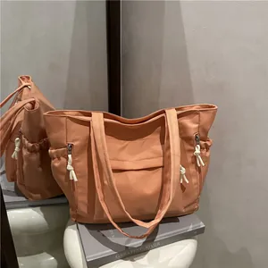 Coral orange high-capacity nylon tote bag with side zipper pockets and rope details