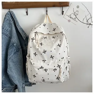 Détail d'un sac à dos blanc crème avec motifs de nœuds noirs et étiquette fashion