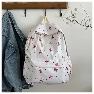 Détail d'un sac à dos blanc à motifs de nœuds rouges avec poches de rangement