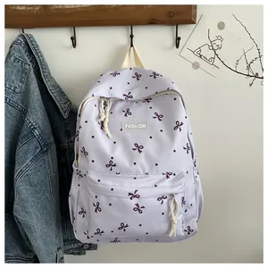 Gros plan d'un sac à dos violet clair à nœuds papillon avec étiquette FASHION
