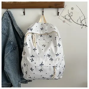 Gros plan d'un sac à dos blanc avec imprimé nœuds noirs et étiquette mode sur crochet bois